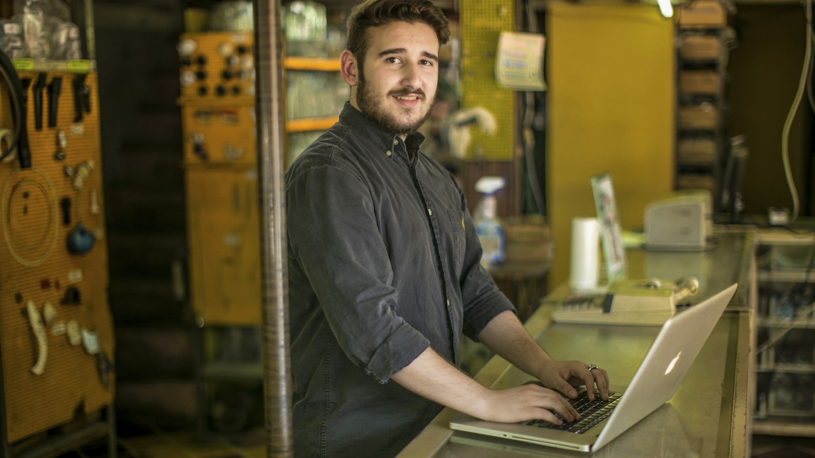 Artisan souriant devant son ordinateur portable dans son atelier