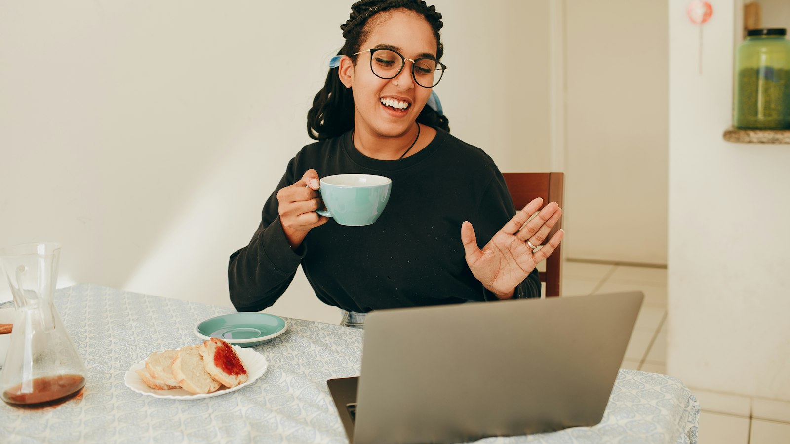 Femme souriante en visioconférence devant son ordinateur, une tasse à la main
